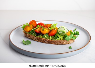 Tasty Open Sandwich From Toasted Sourdough Bread With Mashed Avocado, Slices Of Fresh Cucumber And Cherry Tomatoes