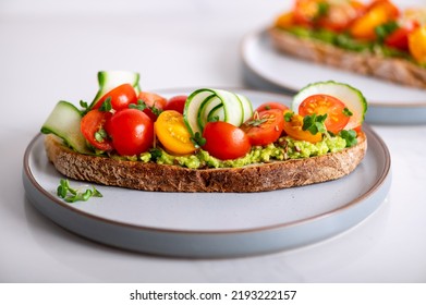 Tasty Open Sandwich From Toasted Sourdough Bread With Mashed Avocado, Slices Of Fresh Cucumber And Cherry Tomatoes