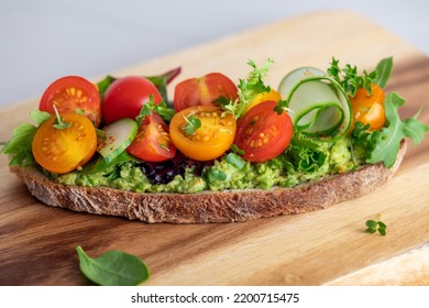 Tasty Open Sandwich From Toasted Sourdough Bread With Mashed Avocado, Slices Of Fresh Cucumber And Cherry Tomatoes