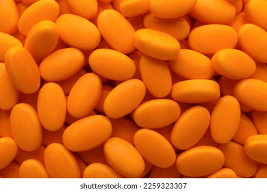 Tasty orange dragee candies as background, top view