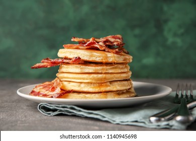 Tasty pancakes with fried bacon on plate