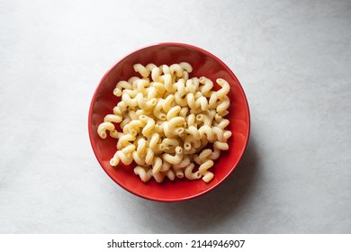 Tasty Pasta In Red Bowl Top View. Pasta Fusilli On White Table. Traditional Italian Cuisine Healthy Food. Simple Fast Carbs Meal Concept.
