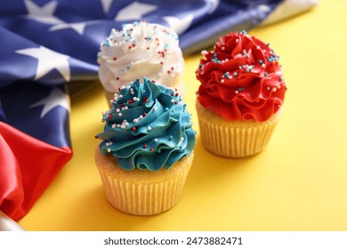 Tasty patriotic cupcakes with USA flag on yellow background. American Independence Day - Powered by Shutterstock