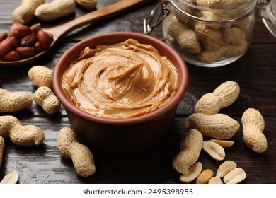 Tasty peanut butter in bowl, groundnuts, jar and spoon on wooden table, closeup - Powered by Shutterstock