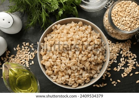 Tasty pearl barley porridge in bowl on dark table, flat lay