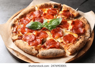 Tasty pepperoni pizza with basil on grey table