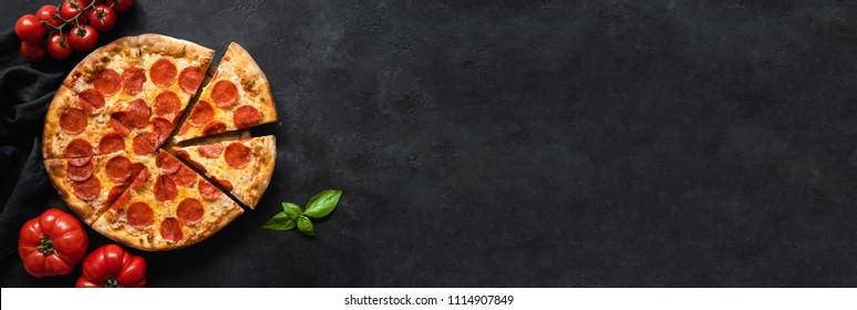 Tasty pepperoni pizza and cooking ingredients tomatoes basil on black concrete background. Top view of hot pepperoni pizza. Banner - Powered by Shutterstock