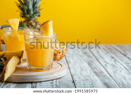 Tasty pineapple juice in glass with ingredients on white wooden table with yellow summer background. Fresh natural pineapple juice cocktail and juice Glass with copy space