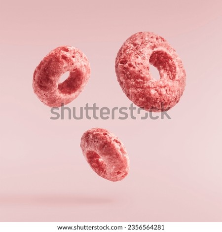 Tasty pink ring Cereals falling in the air isolated on pink background. Food levitation conception. High resolution image