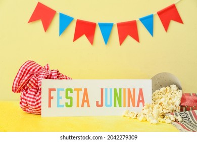 Tasty popcorn with bundle bag and text FESTA JUNINA on color background