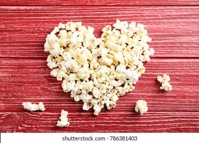 Tasty popcorn on red wooden background, top view