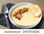 Tasty potato soup with bacon and rosemary in bowl served on wooden table