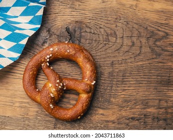 Tasty pretzel with Bavarian flag on a rustic wooden table, Oktoberfest or traditional Bavarian food concept
