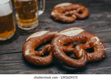 tasty pretzels on dark wooden background with draft beer in the mug in blurred background