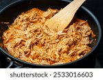 Tasty pulled slow cooked pork meat finishing on frying pan