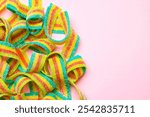 Tasty rainbow sour belts on pink background, top view. Space for text