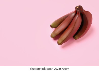 Tasty red baby bananas on pink background, top view. Space for text