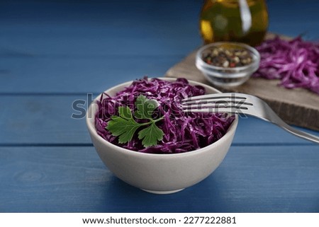 Tasty red cabbage sauerkraut with parsley on light blue wooden table