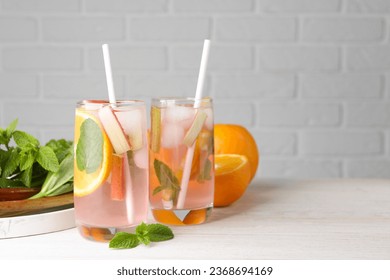 Tasty rhubarb cocktail with orange on white wooden table, space for text - Shutterstock ID 2368694169