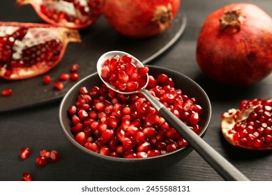 Tasty ripe pomegranates and grains on dark wooden table, closeup - Powered by Shutterstock