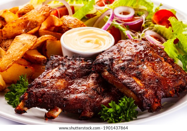 Tasty roasted ribs with baked potatoes vegetables on\
white background 