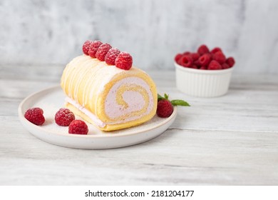 Tasty roll cake, sponge roll, Swiss roll  stuffed with cream cheese ,decorated with fresh raspberries.  - Powered by Shutterstock