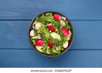 Tasty salad with radish in bowl on blue wooden table, top view - Shutterstock ID 2368694229