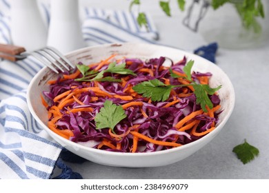 Tasty salad with red cabbage in bowl on light grey table, closeup