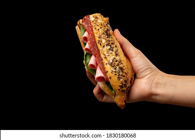 Tasty Sandwich In Baguette With Ham And Salami In Hand