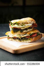 Tasty Sandwich With Meat, Fried Egg, Cheese And Pesto On A Dark Background