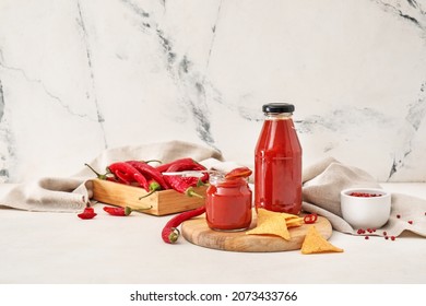 Tasty sauce, nachos, chili peppers and peppercorns on light background - Powered by Shutterstock