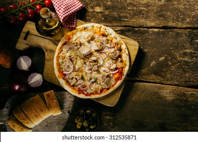 Tasty Seafood Tuna Pizza In A Rustic Kitchen Served With Freshly Baked Sliced Baguette And Condiments, Viewed From Overhead On An Old Wooden Table With Copyspace