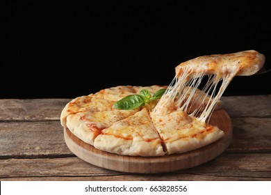 Tasty sliced pizza with basil leaves on wooden table - Powered by Shutterstock