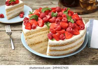 Tasty sponge cake with fresh berries and mint on wooden table, closeup - Powered by Shutterstock