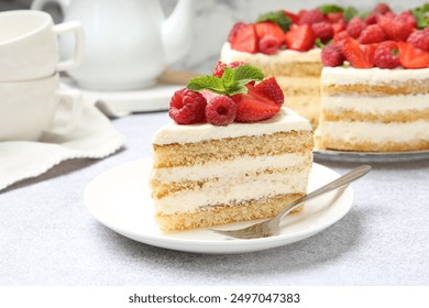 Tasty sponge cake with fresh berries and mint served on light gray table, closeup