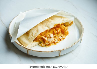 Tasty Street Food - Pita With With Shrimp And Peanut Sauce In Parchment On A White Ceramic Plate On A Marble Background.. Greek Cuisine. Close Up