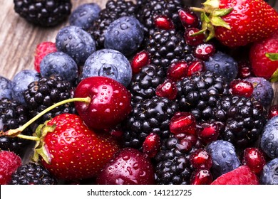  tasty summer fruits on a wooden table. Cherry, Blue berries,  strawberry, raspberries, Blackberries, pomegranate - Powered by Shutterstock