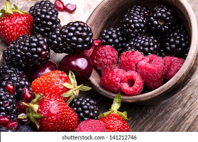  tasty summer fruits on a wooden table. Cherry, Blue berries,  strawberry, raspberries, Blackberries, pomegranate - Powered by Shutterstock