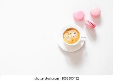 Tasty sweet pink macarons and coffee cup. Macaroons on white background table. Flat lay, top view, copy space