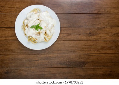 Tasty Tagliatelle Pasta Served With Béchamel Sauce And Basil Leaves. Pasta With White Sauce. Top View Photography With Empty Space For Text.