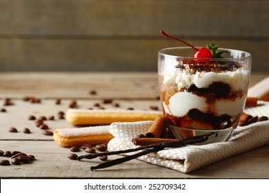 Tasty tiramisu dessert in glass, on napkin, on wooden background - Shutterstock ID 252709342