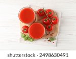 Tasty tomato juice in glasses with fresh vegetables and spices on white wooden table, flat lay