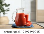 Tasty tomato juice in jug, glass and vegetable on wooden table indoors