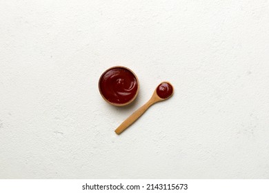 Tasty Tomato Ketchup sauce in wooden bowl with spoon on wood background. Top view with copy space.