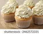 Tasty vanilla cupcakes with cream on table, closeup