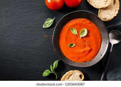 Tasty Vegan Creamy Tomato Soup Decorated With  Basil In Bowl. Served With Bread On Dark Table. View From Above With Copy Space. 