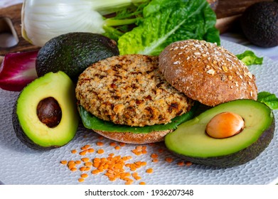 Tasty vegetarian healthy green food, homemade burgers made from orange lentils legumes with green lettuce and fresh ripe avocado