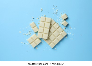 Tasty white chocolate on light blue background, flat lay