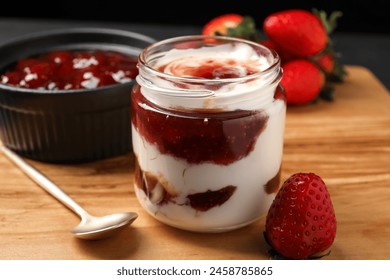 Tasty yoghurt with jam, spoon and strawberries on wooden board, closeup - Powered by Shutterstock