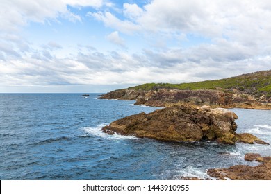 Tathra Wharf Lookout with Ocean Cliffs and rocks on the Far South Coast of NSW, Australia. Sea Coastline with foam and waves and clouds in the sky.